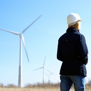 Woman engineer or architect with white safety hat and wind turbines on background